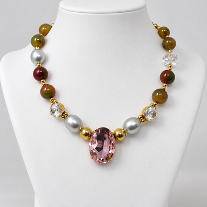 Agate and pearl necklace with a pink oval crystal displayed on a white jewelry bust.