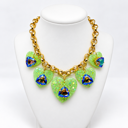 Green heart charm necklace displayed on a white jewelry bust.
