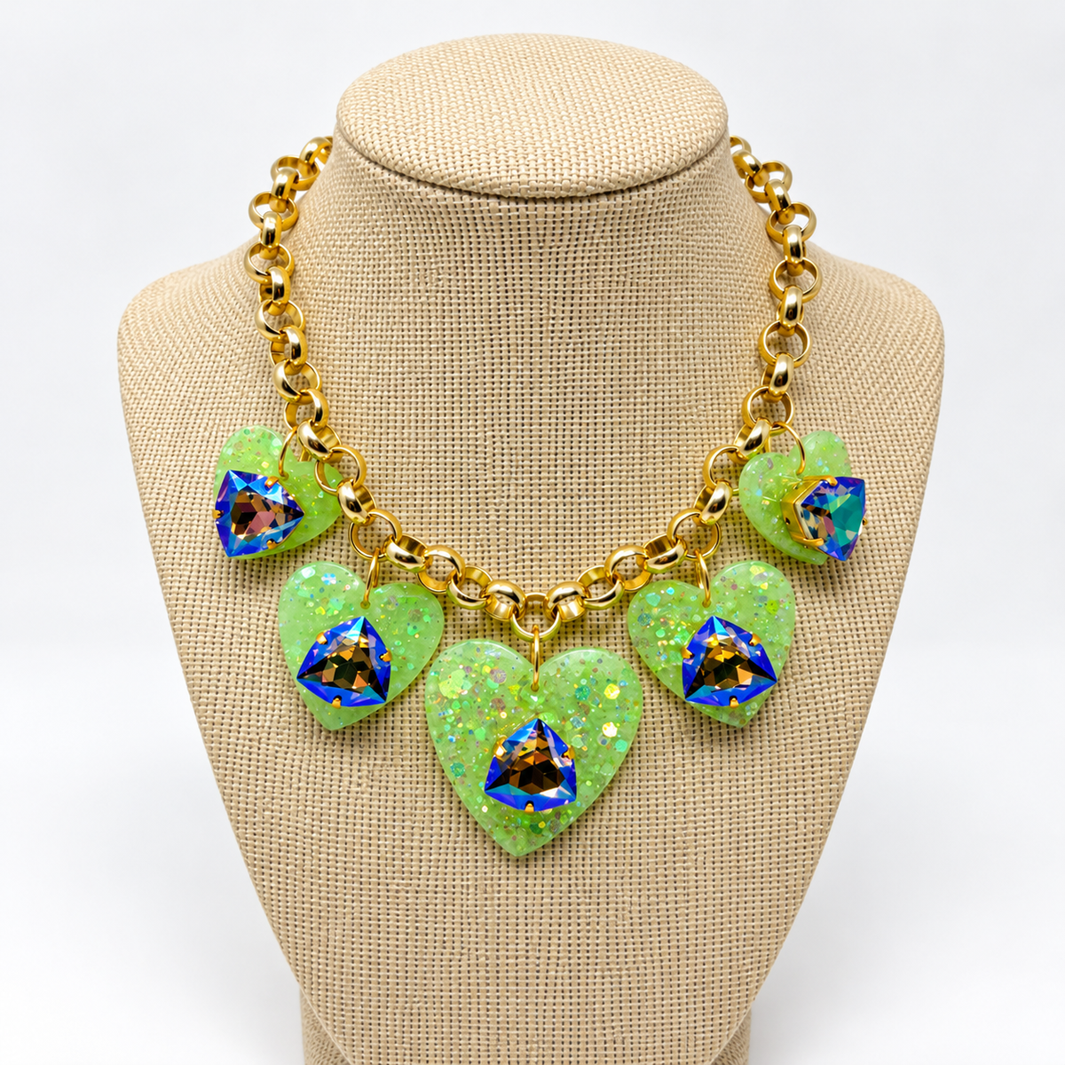 Gold-plated heart charm Swarovski necklace displayed on a linen jewelry bust.