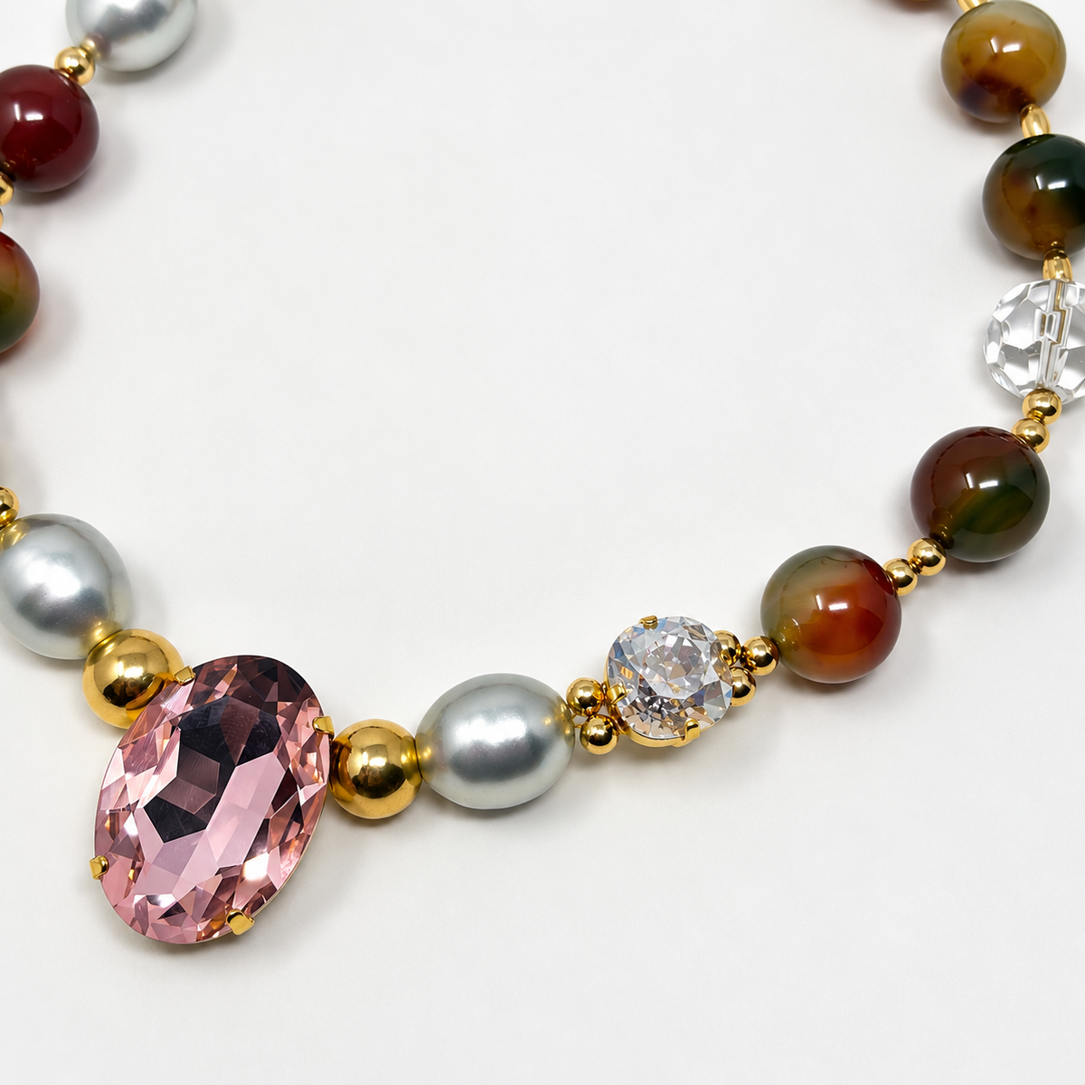 Close-up of pink oval crystal, pearl, clear crystal, and multicolored agate beads.