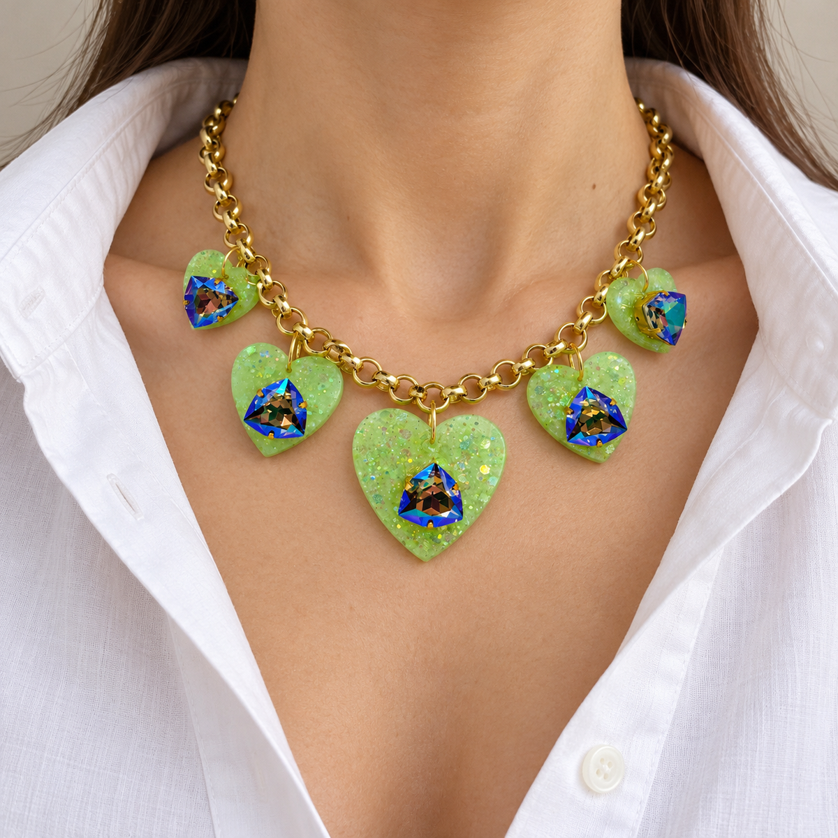 Green heart charm Swarovski crystal necklace worn with a white blouse.