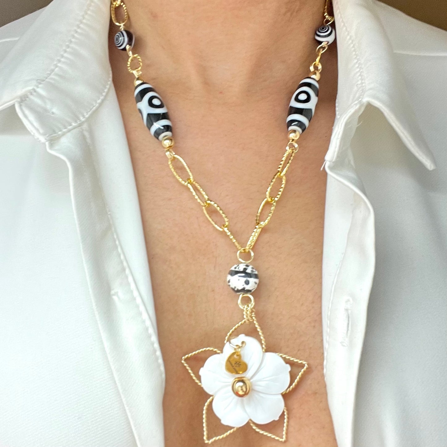 Black and white necklace with gold chain and mother of pearl flower pendant