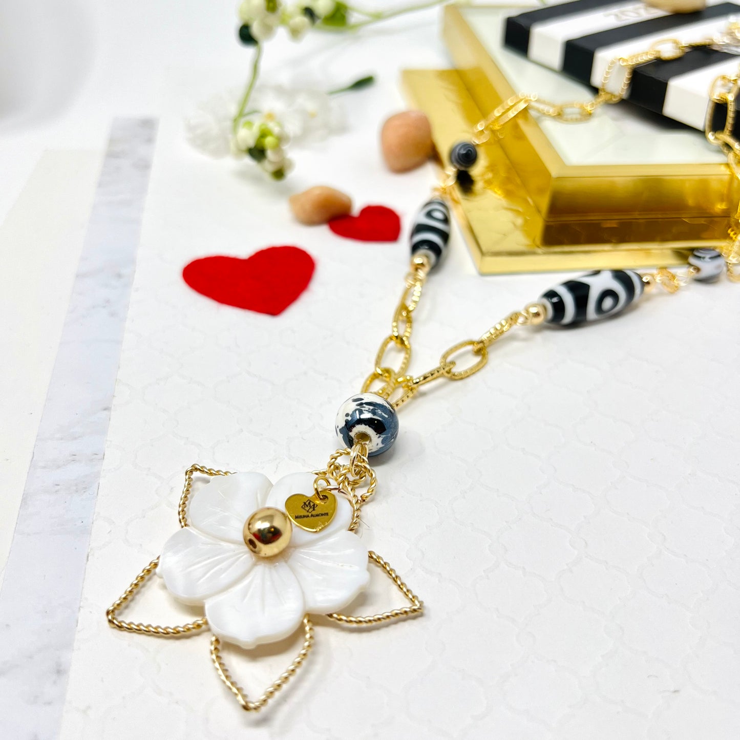 Black and white necklace with gold chain and mother of pearl flower pendant