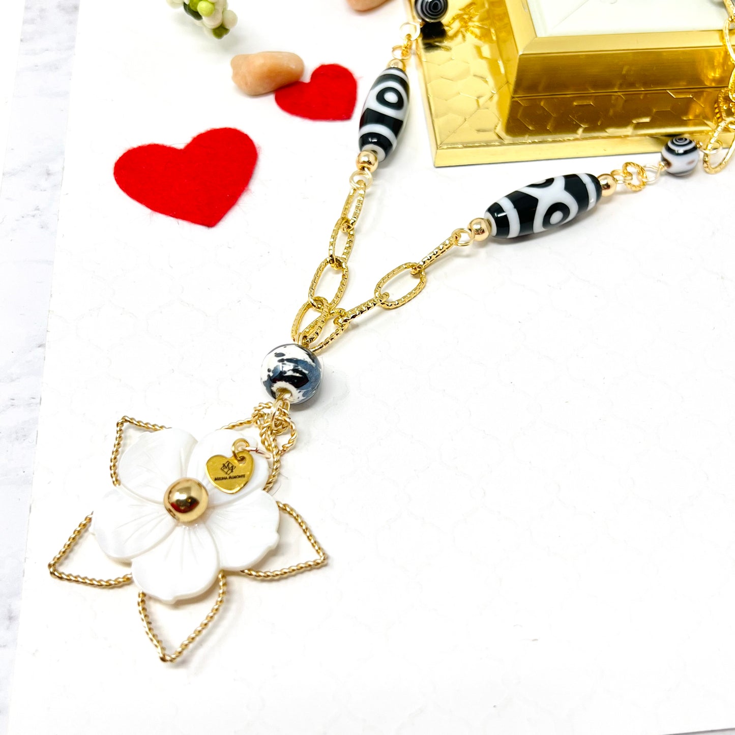 Black and white necklace with gold chain and mother of pearl flower pendant