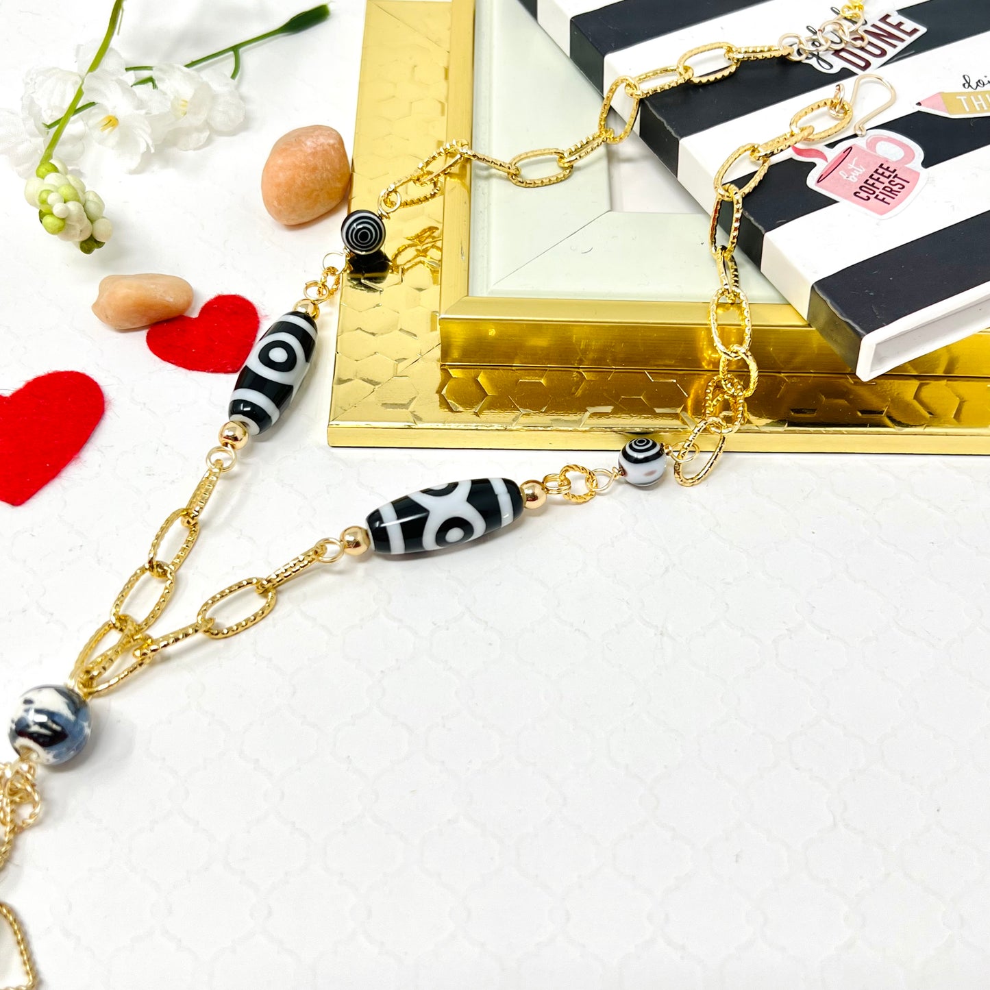 Black and white necklace with gold chain and mother of pearl flower pendant