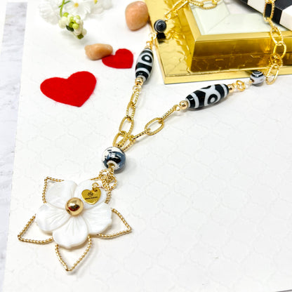 Black and white necklace with gold chain and mother of pearl flower pendant