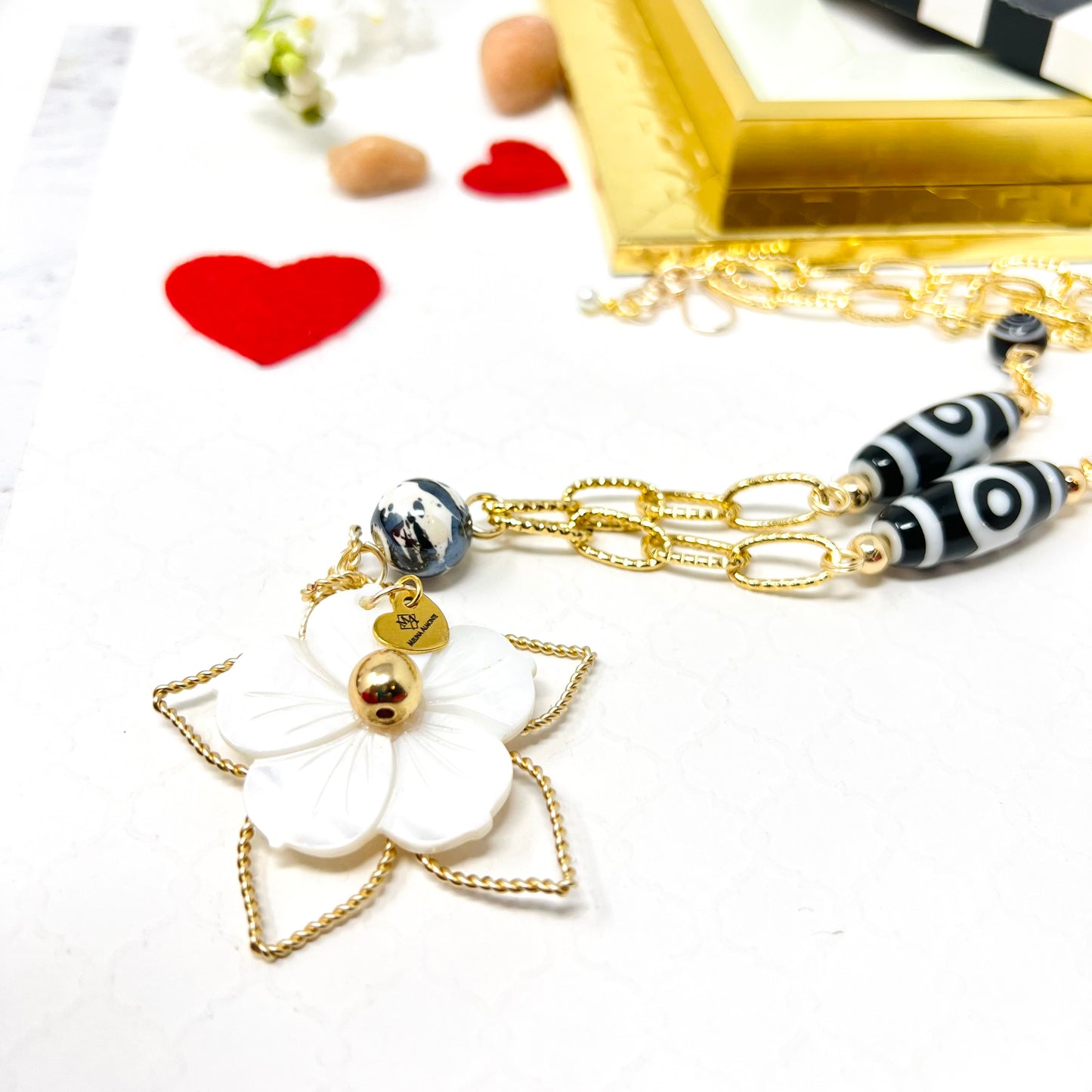 Black and white necklace with gold chain and mother of pearl flower pendant