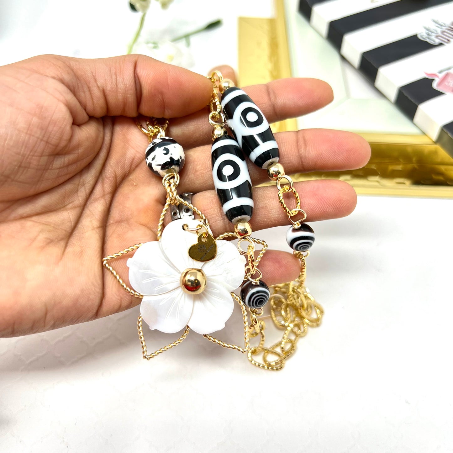 Black and white necklace with gold chain and mother of pearl flower pendant