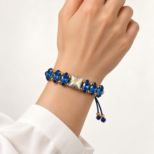 Blue navette crystal bracelet with an iridescent square center crystal and adjustable cord, shown on the wrist.