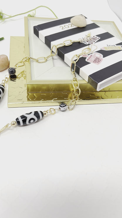 Black and white necklace with gold chain and mother of pearl flower pendant